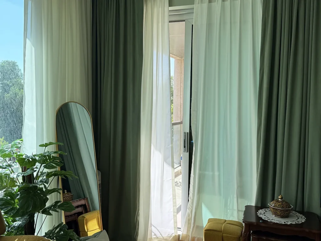 Green blackout and white sheer double curtains in a Dubai apartment